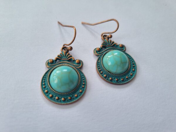 These bronze earrings featuring a marble drop center and intricate bronzed detail